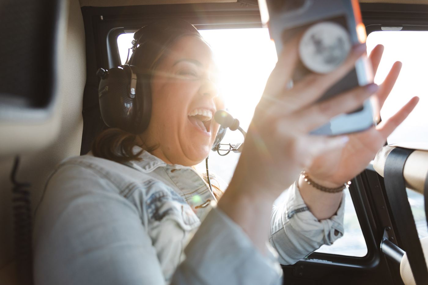Passenger laughing and taking photos on a helicopter ride over Kansas City at golden hour